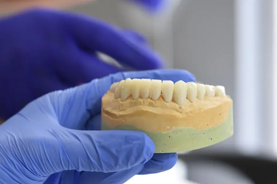 Ceramic dental crown being finished by hand in the laboratory